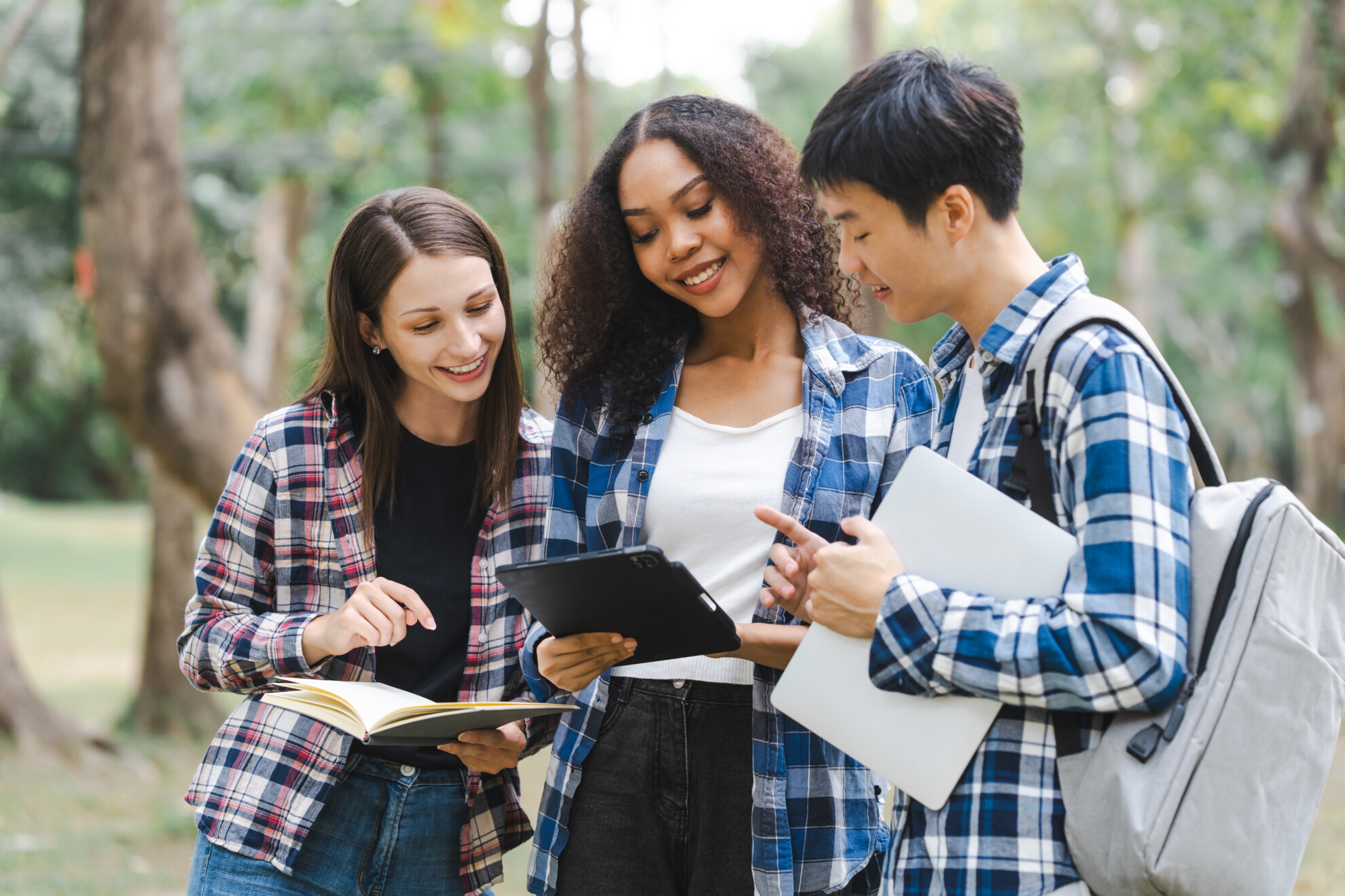 Group of young interracial diverse university students chatting together outside, engaging in a discussion together, college campus, enjoying campus recreation. Happy friends